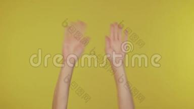 女人的手挥舞着，用她的手指随着音乐节奏的手势在演播室的黄色背景上隔离<strong>开来</strong>。 复制空间